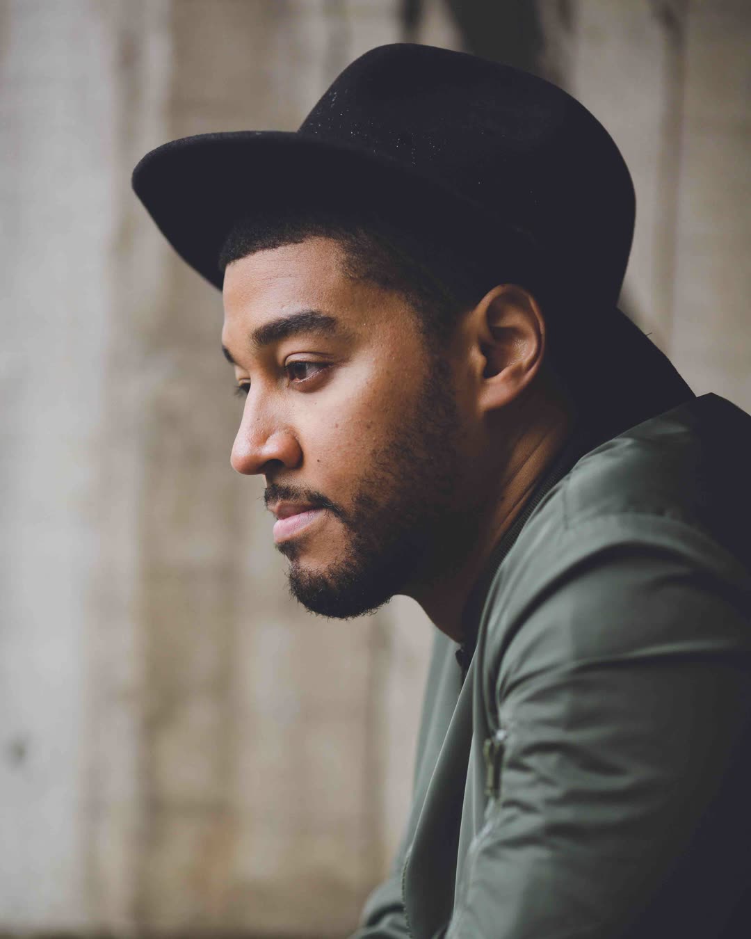 Kwame in a dark hat and jacket, in profile